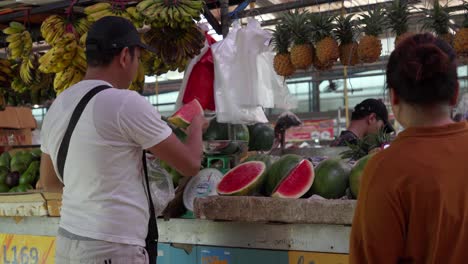 Vendedor-En-Mercado-Indonesio-Pone-Sandía-En-Bolsa-De-Plástico,-Cámara-Lenta