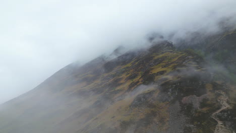 Aerial-flying-backwards-through-fog-over-mountain,-Glen-Coe,-Scotland