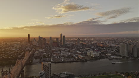 NYC-New-York-Aerial-v368-flyover-East-river-capturing-Roosevelt-Island,-Queensboro-Bridge,-Queens-cityscape-with-golden-glowing-sun-rising-on-the-horizon---Shot-with-Mavic-3-Pro-Cine---September-2023