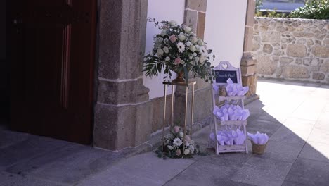 Entrance-of-a-church-decorated-with-a-flower-arrangement-and-cones-of-petals-for-a-wedding