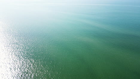 Stunning-aerial-drone-shot-of-sunlight-shining-across-surface-of-vast-ocean-during-morning-time