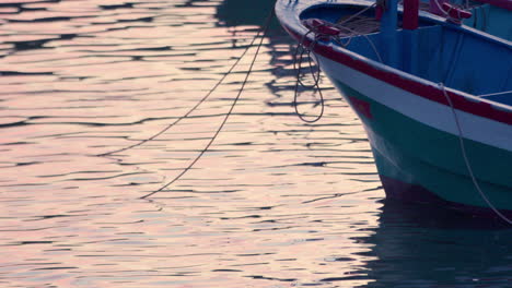 Colorful-wooden-boat-moored-at-port-of-lake-sea-ocean-during-warm-afternoon-light-golden-hours