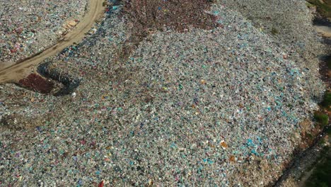 Drone-flyover-a-sprawling-landfill-with-vast,-unsorted-waste-piles,-showcasing-environmental-sustainability-concerns,-microplastics-and-consequences-of-global-warming-and-climate-change,-aerial-shot