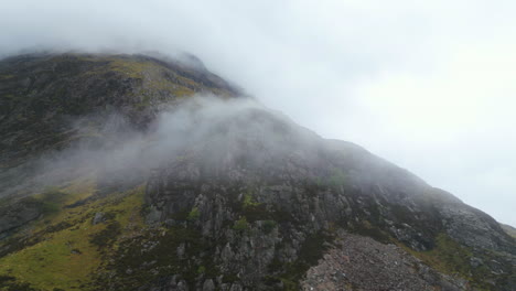 Aerial-flying-backwards-from-cloud-covered-mountain,-Glen-Coe,-Scotland