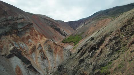 Aerial-view-of-the-colorful-Golden-Canyon-in-Hvannagil-during-summer-in-Iceland,-highlighting-the-vibrant-hues-and-rugged-terrain