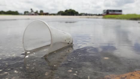 Plastic-cup-thrown-away-in-water-puddle,-pollution