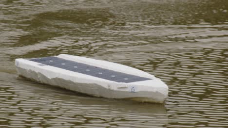 Close-up-a-styrofoam-RC-solar-panel-boat-racing-through-water