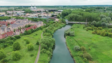 Aerial-shot-of-bridge-over-a-canal-with-luxury-houses-and-apartments-and-surrounded-with-greenery-in-England