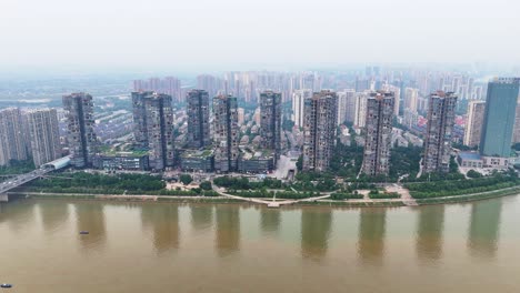 Aerial-fly-by-at-the-riverfront-in-Changsha,-Hunan-province-in-a-residential-area