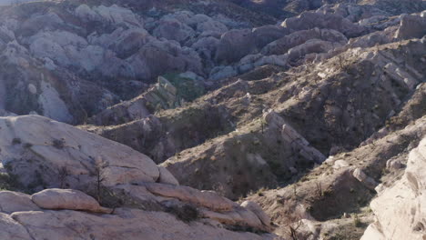 The-contours-of-the-ground-in-the-Devil's-Punchbowl-Arch,-backward-drone-shot