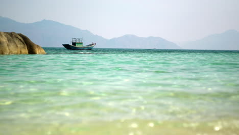 Vista-De-La-Playa-Paradisíaca-De-Ensueño-Del-Barco-A-Distancia-En-Aguas-Cristalinas-Del-Mar-Y-Del-Océano