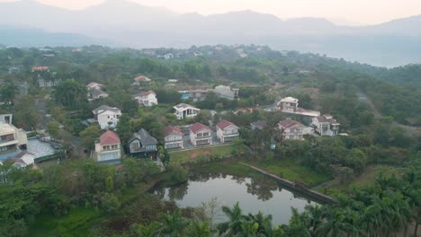 Rise-from-dense-palm-tree-stand-to-Aamby-Valley-City-in-Pune-India,-aerial