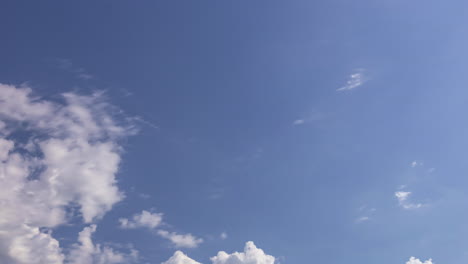 Eine-Aufnahme-Aus-Niedrigem-Winkel-Von-Hellen,-Weißen-Wolken,-Die-Im-Zeitraffer-Den-Ganzen-Tag-über-Am-Blauen-Himmel-Entlanggleiten