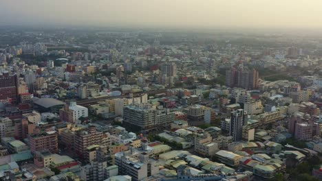 Aerial-drone-flyover-the-neighborhood-capturing-the-urban-cityscape-of-residential-and-commercial-buildings-of-Douliu-city,-Yunlin-County,-Taiwan-at-sunset