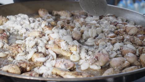 Slow-motion-shot-of-a-chef-stirring-a-large-pan-full-of-fish-and-chicken-things