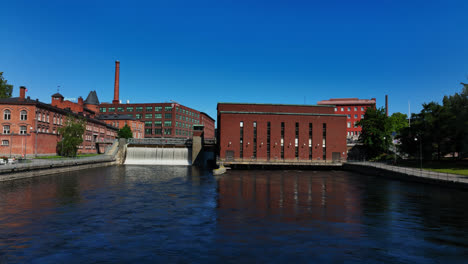 AERIAL:-in-front-of-the-Tammerkoski-dam,-sunny,-summer-day-in-Tampere,-Finland