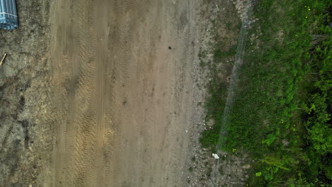 Aerial-drone-top-down-shot-over-an-empty-dirt-road-with-road-been-constructed-on-it-at-daytime