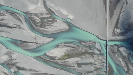 Aerial-view-of-a-car-driving-through-the-Ring-Road-across-a-blue-glacier-river-from-above-in-Iceland-during-summer