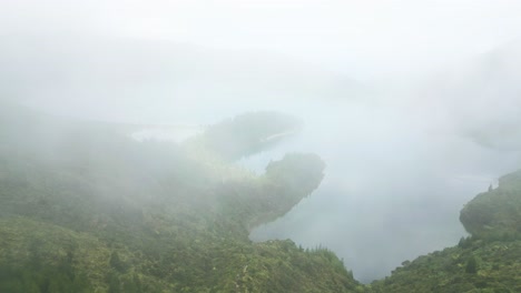 Foggy-aerial-view-of-Lagoa-do-Fogo's-lush-green-landscape-and-serene-water-in-the-Azores