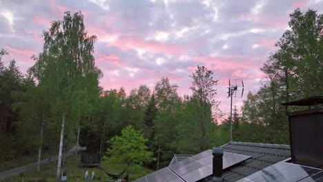 Dramatic-cloudy-dusk-sky-and-house-roof-full-of-Photovoltaic-cells---Aerial-view