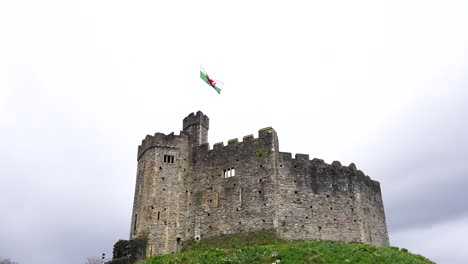 Norman-Fortress-of-Cardiff-Castle,-Welsh-flag-with-dragon-waving-against-wind