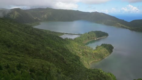 Lagoa-do-fogo's-serene-waters-and-lush-greenery-under-a-partly-cloudy-sky,-aerial-view