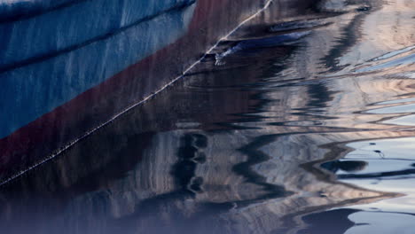 Wooden-boat-water-reflection-on-still-ocean-sea-lake-water