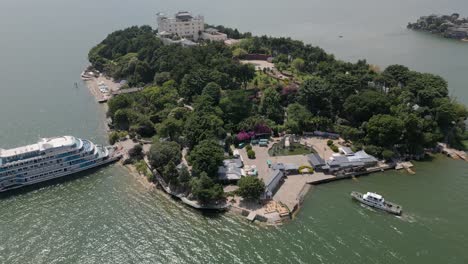 Drone-footage-of-a-small-boat-docking-into-Nanzhao-Amorous-Island-in-Dali,-China