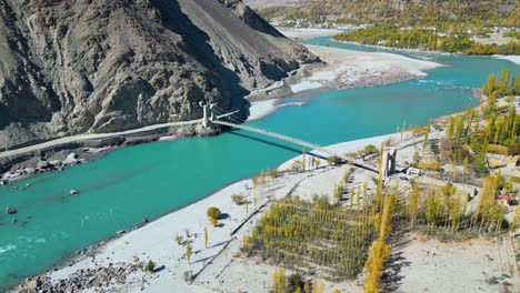 Atemberaubende-Luftaufnahme-Einer-Brücke-über-Einen-Blauen-Fluss-Inmitten-Zerklüfteten,-Felsigen-Geländes