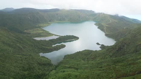 Lush-green-mountains-surrounding-Lagoa-do-Fogo,-a-serene-volcanic-crater-lake-in-the-Azores