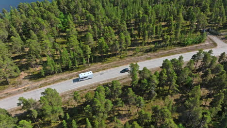 AERIAL:-Car-passing-a-RV-on-a-boreal-road-at-lake-Inari,-summer-day-in-Finland