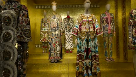 Elegant-mannequins-showcase-a-collection-of-luxurious,-intricate,-and-colorful-designer-fashions-in-an-opulent-gold-setting,-highlighting-artistry-and-craftsmanship