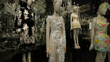 Elegant-mannequins-showcase-a-collection-of-luxurious,-intricate,-and-colorful-designer-fashions-in-an-opulent-gold-setting,-highlighting-artistry-and-craftsmanship