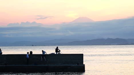 Paisaje-Típico-En-El-Océano-En-Japón-Durante-La-Puesta-De-Sol-Con-Gente-Y-El-Monte-Fuji