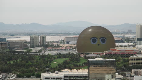 Weite-Aufnahme-Eines-Verspielten-Riesigen-Smiley-Gesichts-Auf-Der-Las-Vegas-Sphere,-Das-Hinreißend-In-Den-Wüstenhimmel-Blickt