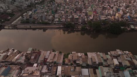 Urban-density-along-canal-in-poor-area-of-Ho-Chi-Minh-City,-Vietnam-showing-shacks-and-slum-rooftops-in-late-afternoon-light