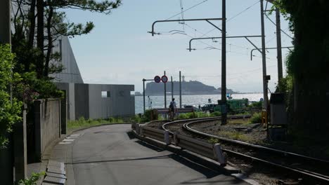 Hermosas-Vías-De-Tren-De-Enoden-Con-El-Océano-Y-La-Isla-De-Enoshima-En-La-Distancia