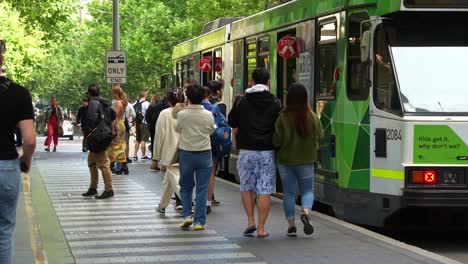 Massive-crowds-of-passengers-disembarking-and-boarding-the-tram-at-the-stop-in-front-of-State-Library-Victoria-along-Swanston-street,-in-the-bustling-Melbourne-central-business-district