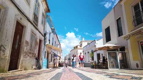 People-walking-in-a-colorful-street-in-Lagos,-Portugal-on-a-sunny-day,-timelapse