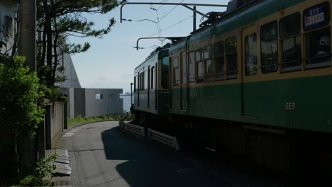 Enoden-train-driving-out-toward-ocean-with-Enoshima-in-distance