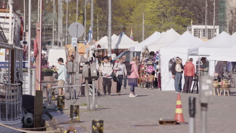 People-moving-around-Helsinki-market-square-and-its-vendors-in-daytime,-static