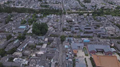 Aerial-footage-of-a-pedestrian-street-in-Dali's-Ancient-City,-followed-by-a-reveal-of-the-towering-and-magnificent-Cang-Shan-Mountain-that-looms-over-the-city