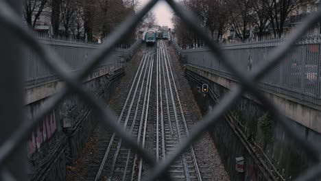 Metro-train-speeding-down-into-tunnel,-seen-from-behind-a-fence-in-Paris