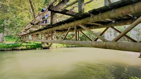 Tourist-Panega-River-trip-boat-passes-under-rustic-wooden-footbridge