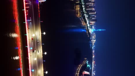 Colorful-lights-illuminating-the-bridge-over-the-Binhe-River-in-Linyi-City,-Shandong-Province,-night-aerial