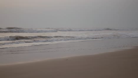 Soft-waves-gently-lap-against-the-sandy-shore-of-a-tranquil-beach-in-the-evening