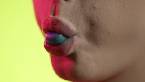 mouth-close-up-of-woman-chewing-bubblegum-and-blowing-bubble,-close-up-shot-on-yellow-background