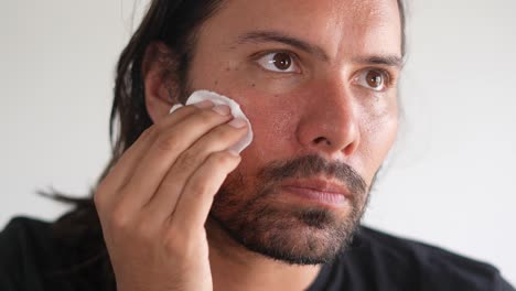 skin-care,-Latino-man-wiping-his-face-with-cotton-swab,-face-cleaning