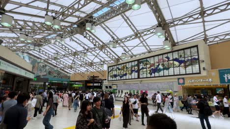 Busy-train-station-with-people-walking-and-standing-under-a-modern-glass-ceiling