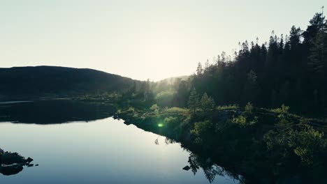 Mjøvatnet,-Indre-Fosen,-Trøndelag,-Norway---An-Enchanting-Panorama-With-Sunlight-Radiating-Over-the-Lake-and-the-Surrounding-Nature,-Their-Reflections-Visible-in-the-Water---Drone-Flying-Forward